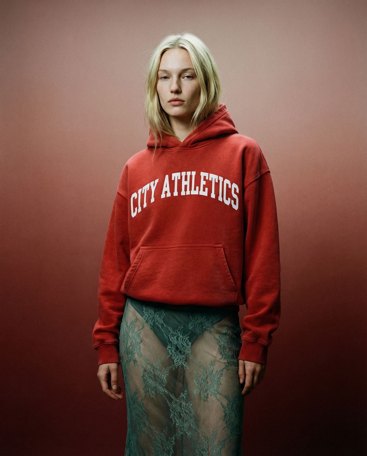 a woman in a red sweatshirt and green skirt