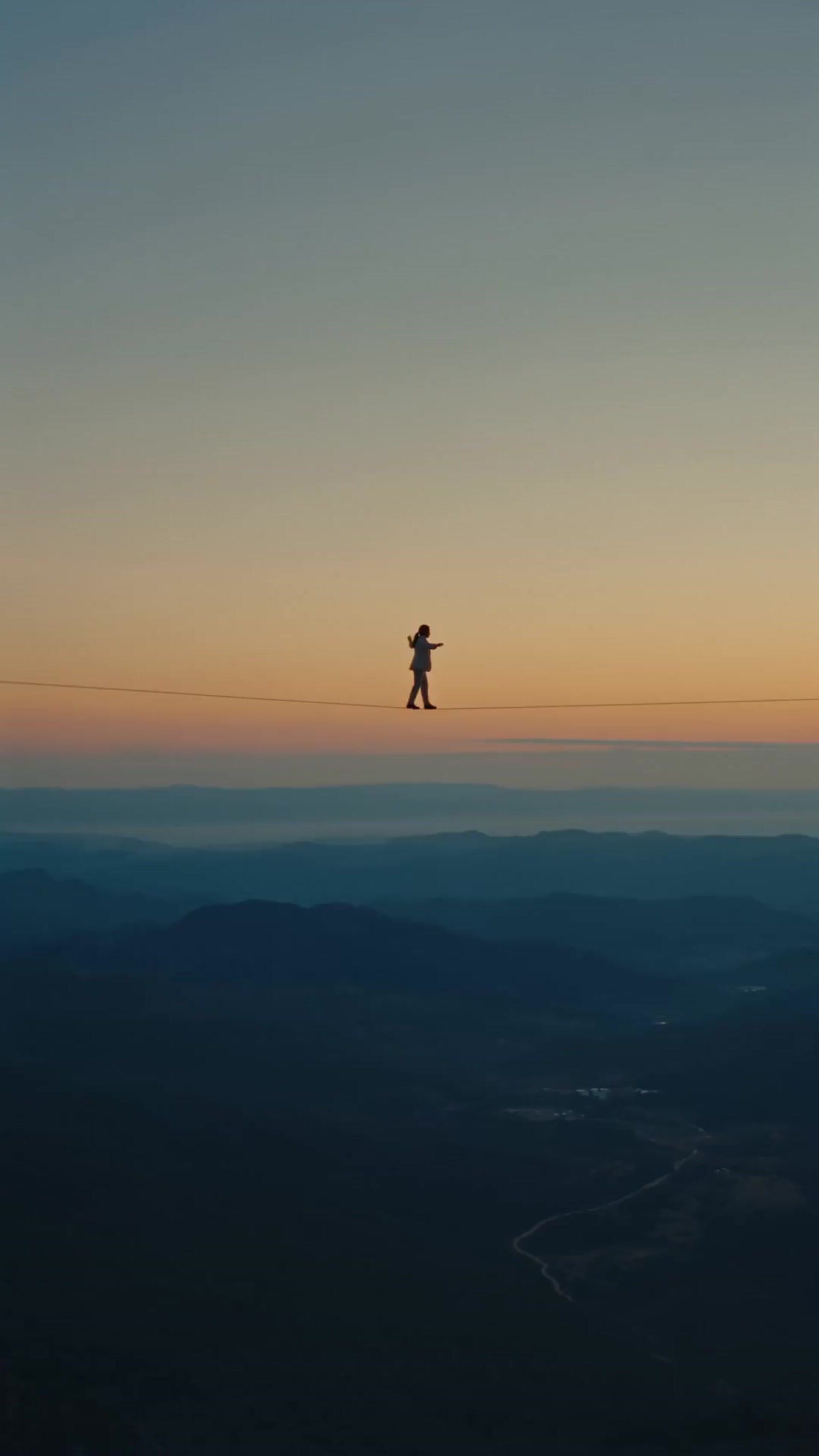 a person standing on a wire above a valley