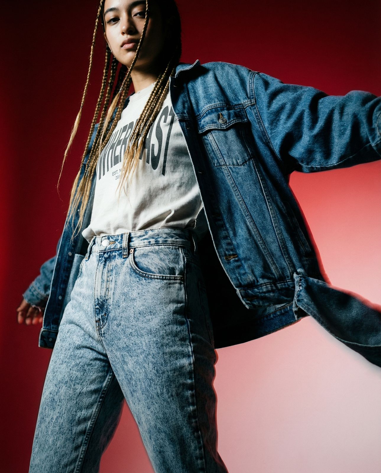 a woman with dreadlocks standing in front of a red background