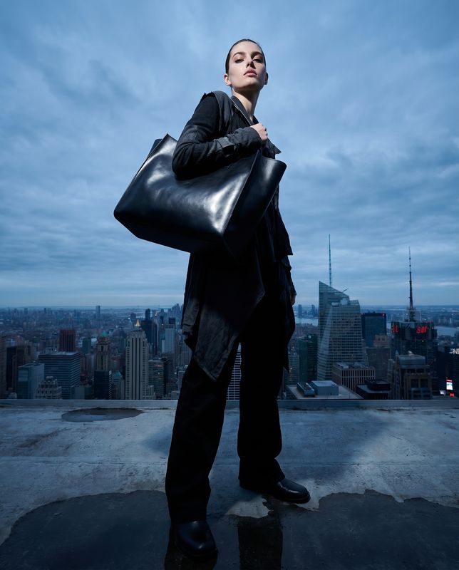 a woman holding a large black bag on top of a building