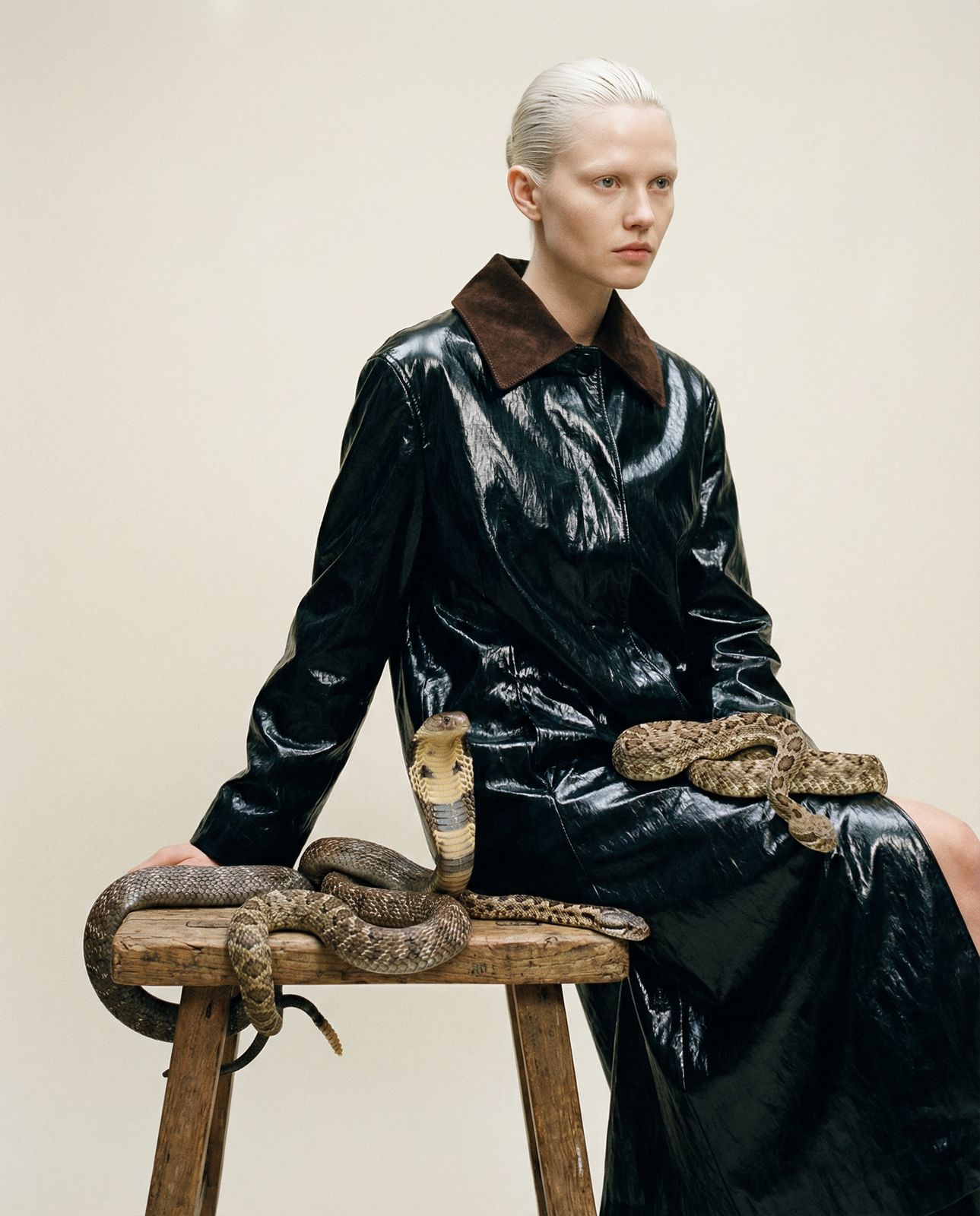 a woman sitting on a stool with a snake on her lap