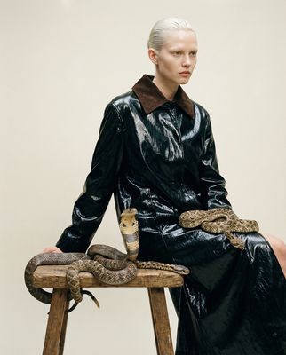 a woman sitting on a stool with a snake on her lap
