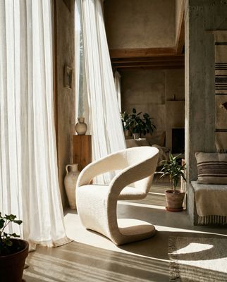 a white chair sitting in a living room next to a window