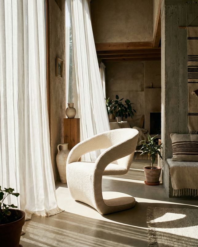 a white chair sitting in a living room next to a window