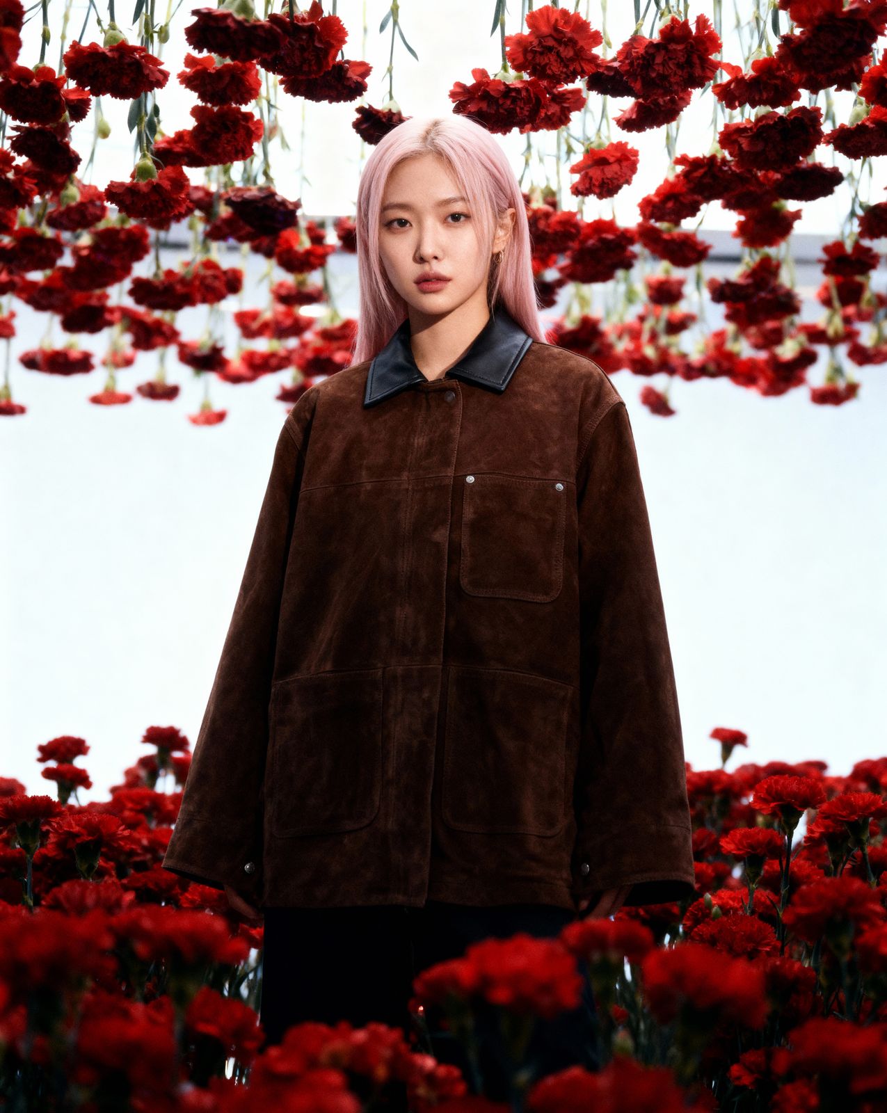 a woman with pink hair standing in a field of flowers