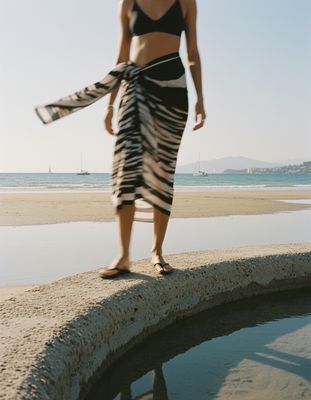 a woman in a black and white skirt standing on a rock