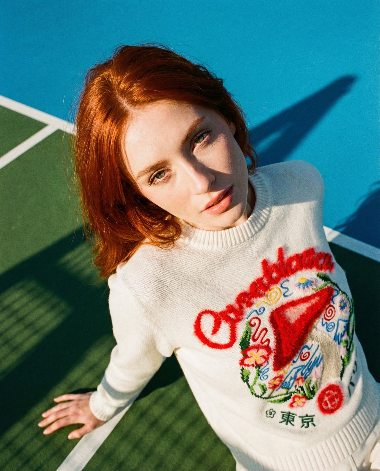 a woman with red hair is posing on a tennis court