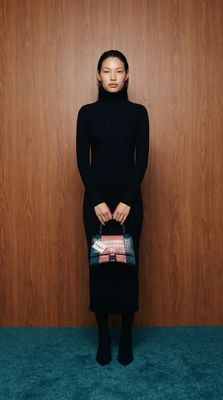 a woman in a black dress holding a purse