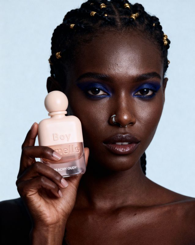 a woman holding a bottle of perfume in front of her face
