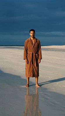 a man in a bathrobe standing on a beach