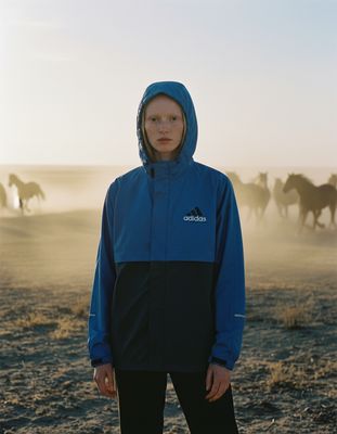 a person standing in a field with horses in the background