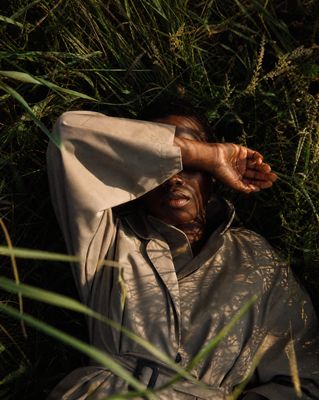 a man laying in the grass with his hands on his head