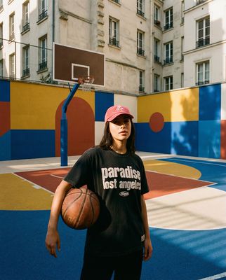 a woman holding a basketball in front of a basketball court