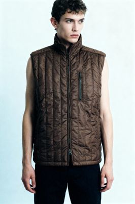 a young man wearing a brown quilted vest