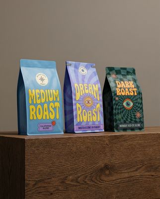 three bags of coffee sitting on top of a wooden table