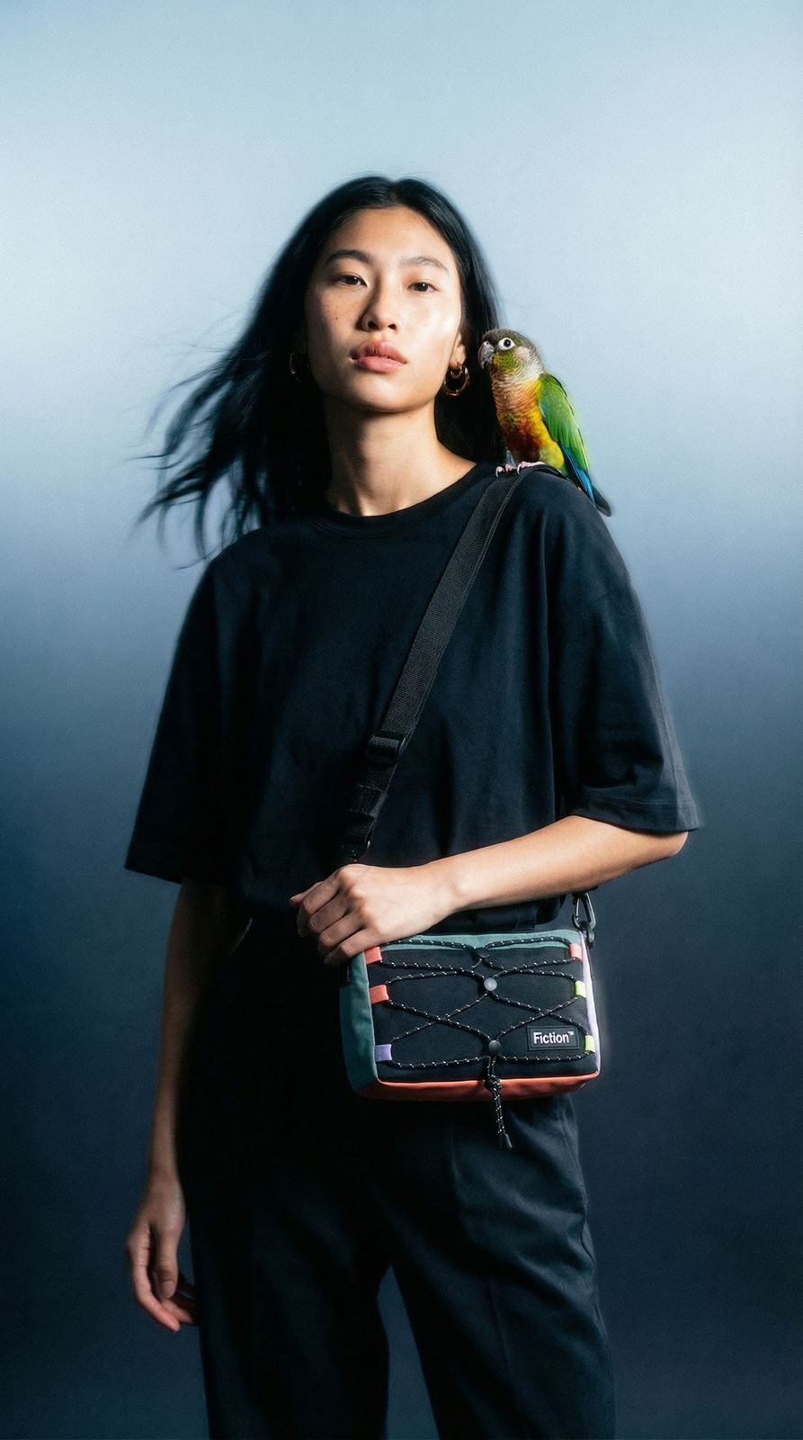 a woman holding a bird on her shoulder