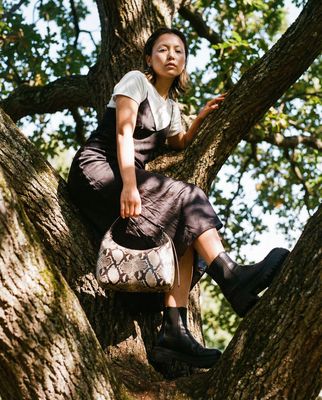 a woman sitting in a tree holding a purse