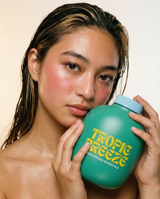 a young woman holding a green bottle of shampoo