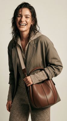 a woman holding a brown purse and smiling