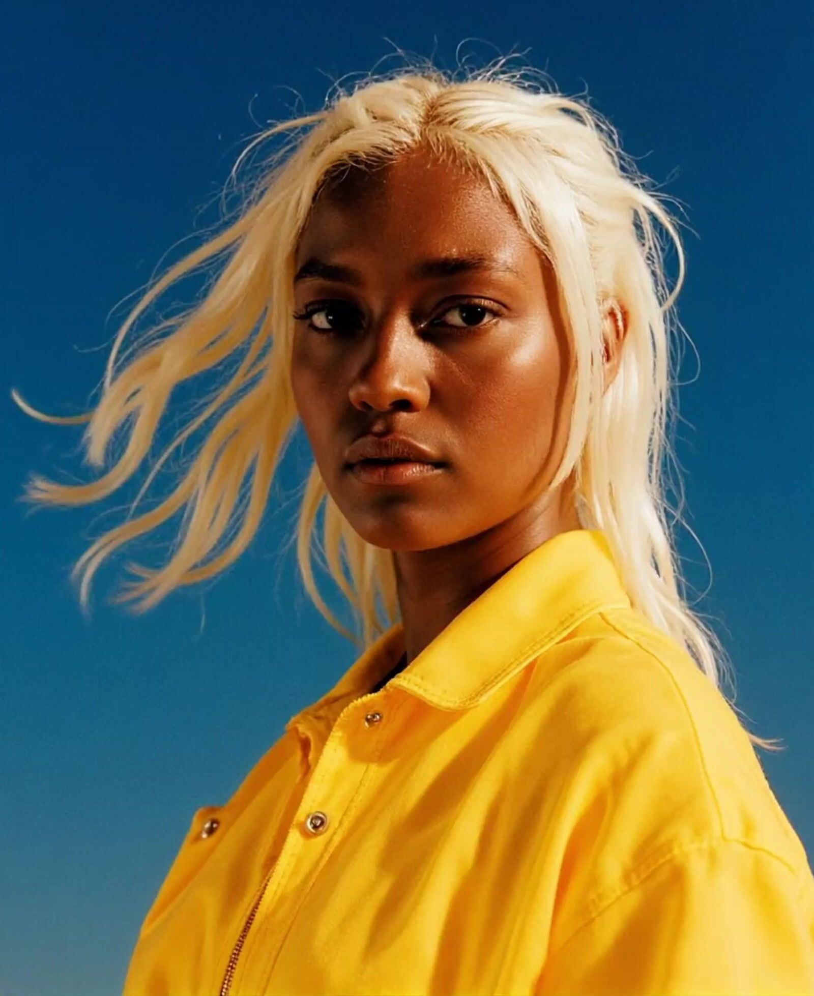 a woman with blonde hair wearing a yellow shirt