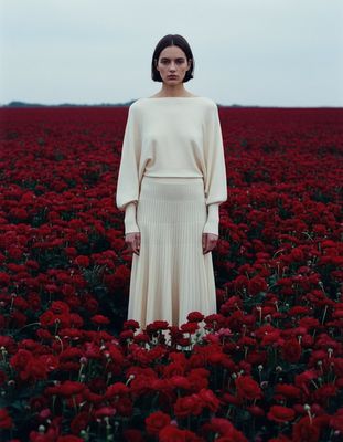 a woman standing in a field of red flowers