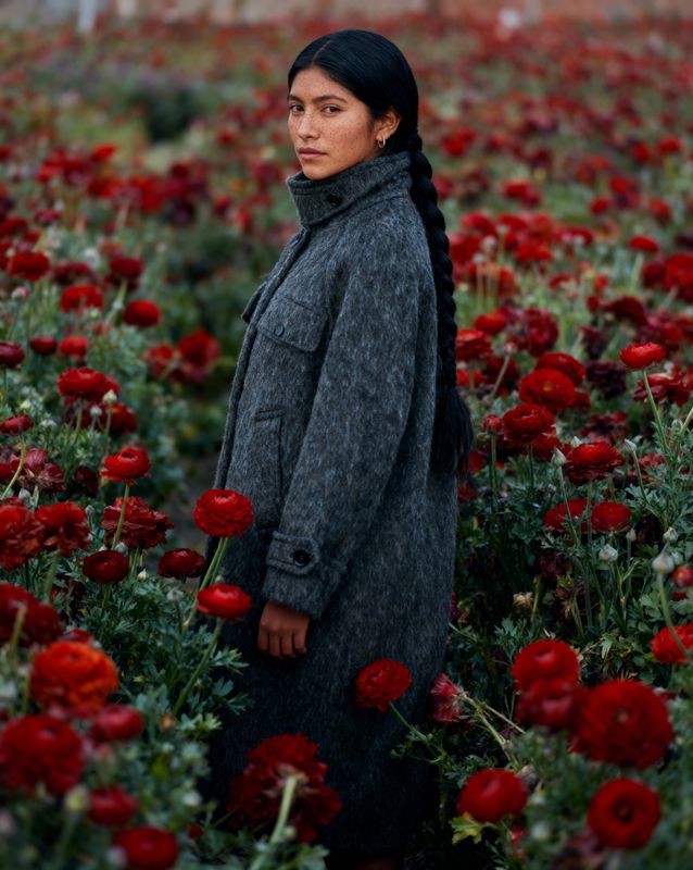 a woman standing in a field of red flowers