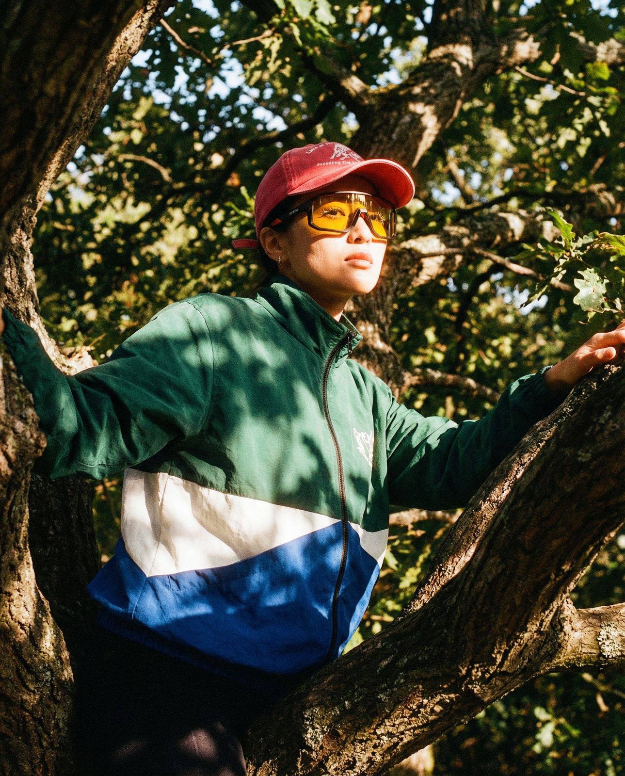 a man in a red hat and sunglasses standing on a tree branch