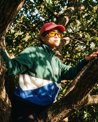 a man in a red hat and sunglasses standing on a tree branch