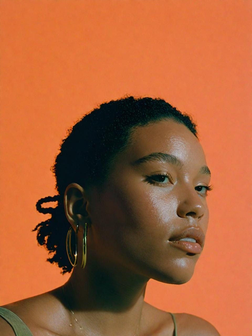 a woman in a green tank top and gold hoop earrings