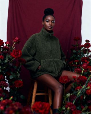 a woman sitting on a stool surrounded by flowers