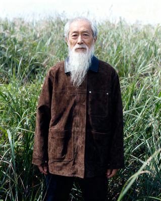 a man with a long white beard standing in a field