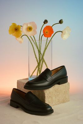 a pair of shoes sitting next to a vase with flowers in it