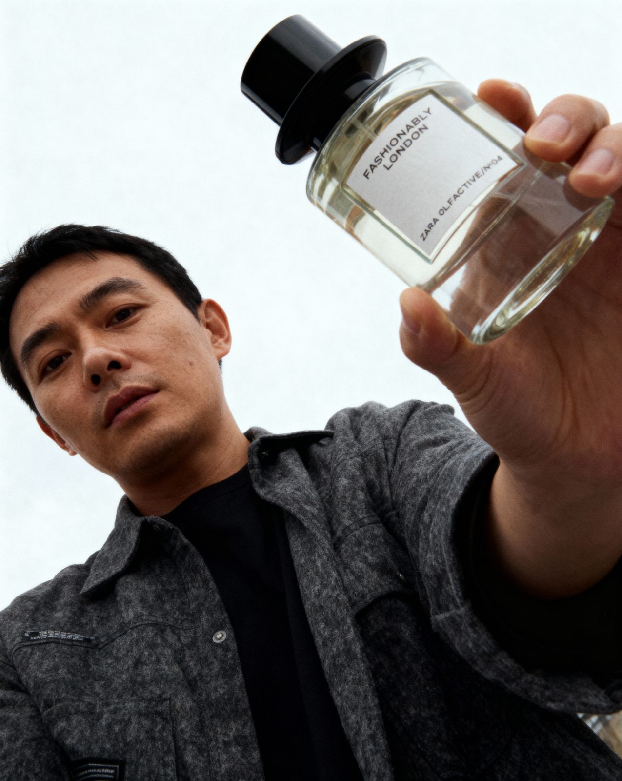 a man holding a bottle of perfume in his hand