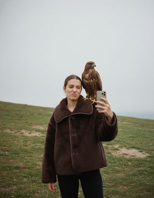 a woman holding a bird of prey in her hand