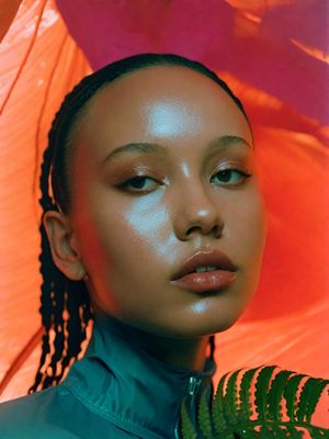 a woman with braids standing in front of an umbrella