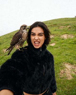a woman holding a bird on her shoulder