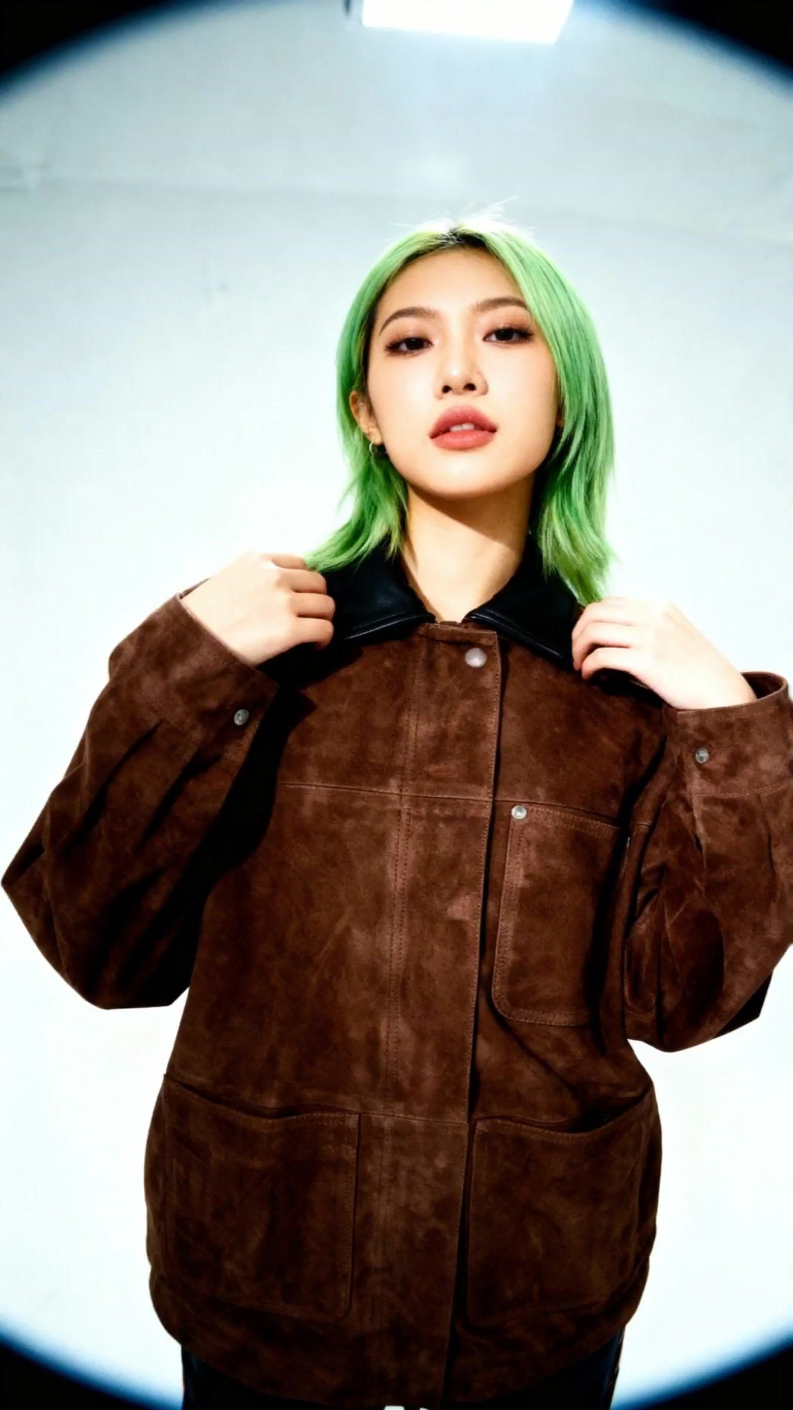 a woman with green hair wearing a brown jacket