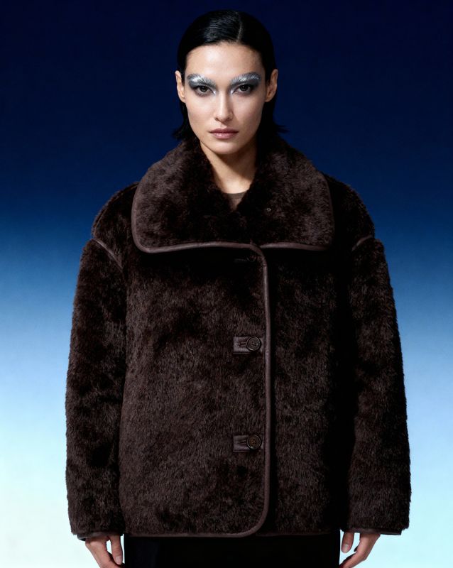 a woman wearing a brown coat and black pants