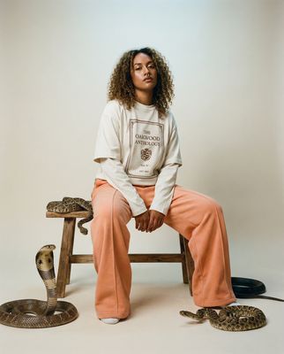 a woman sitting on a stool next to a snake