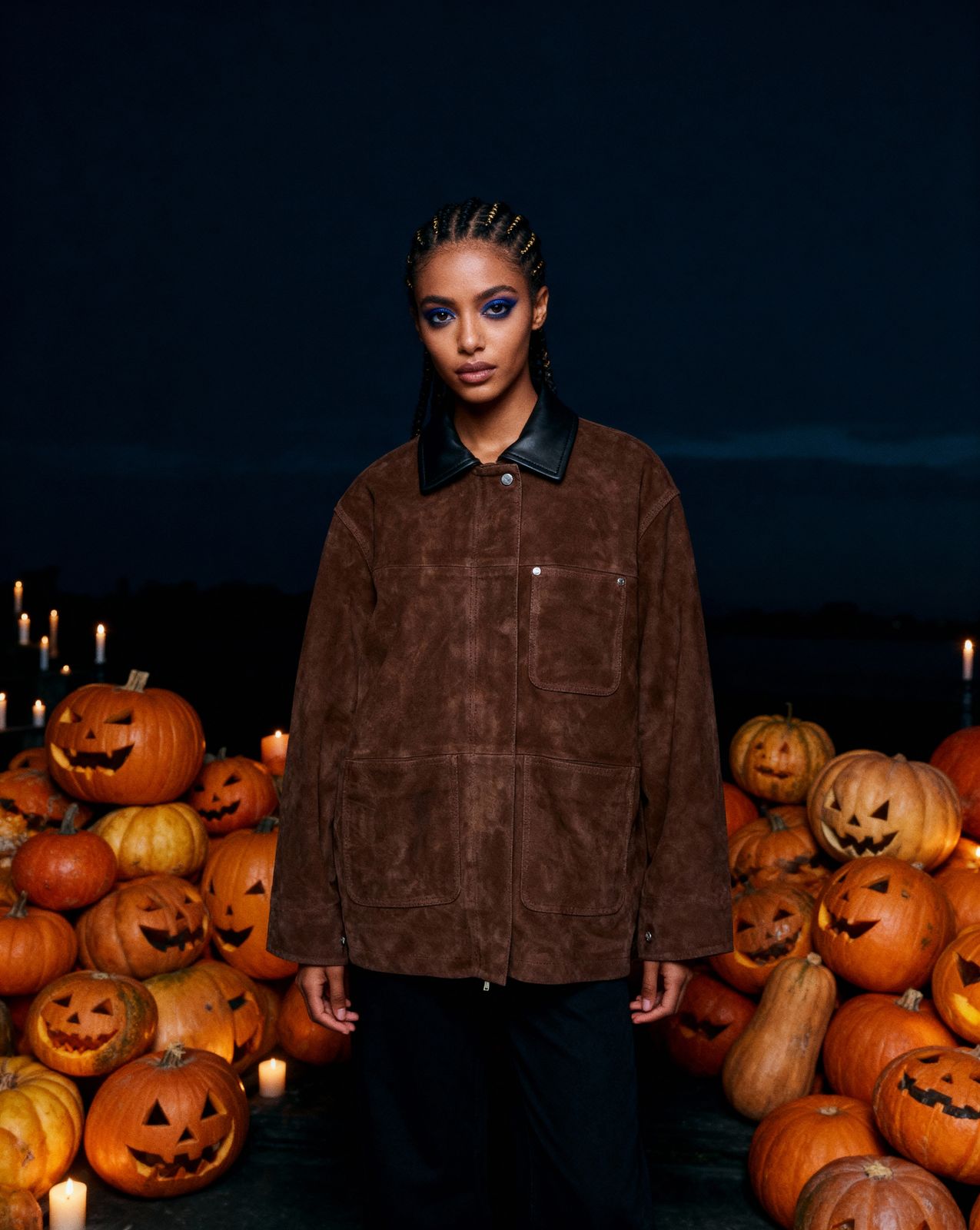 a woman standing in front of a pile of pumpkins