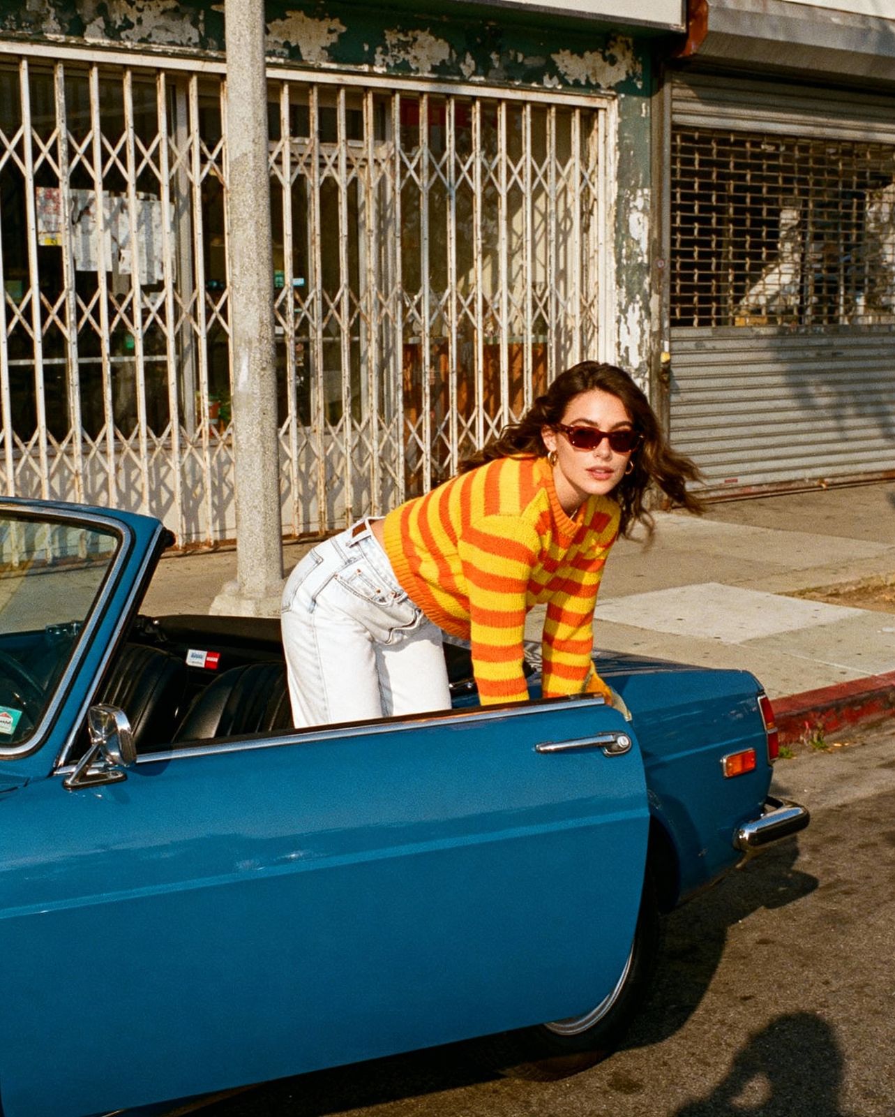 a woman in a striped shirt leaning out of a blue car