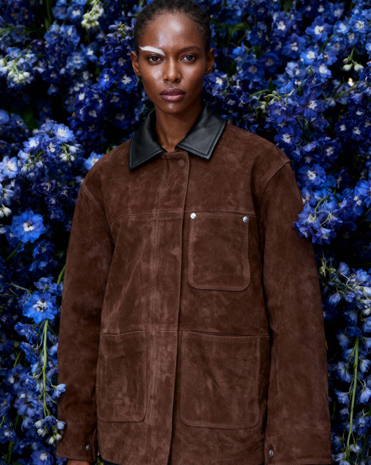 a woman standing in front of blue flowers