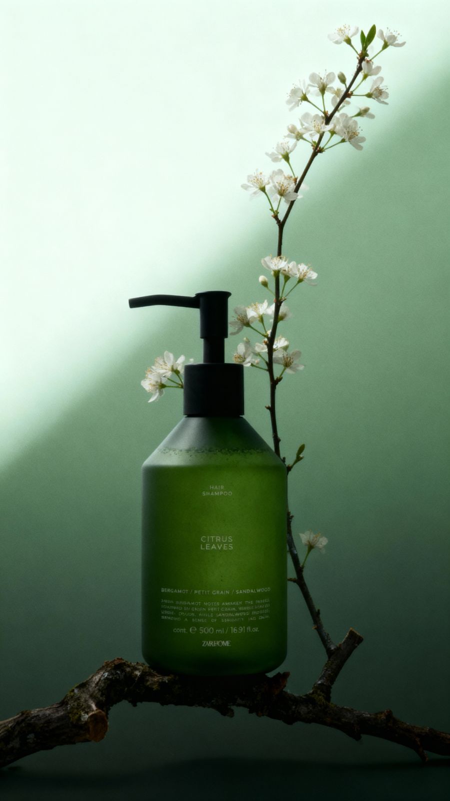 a bottle of green liquid sitting on top of a tree branch