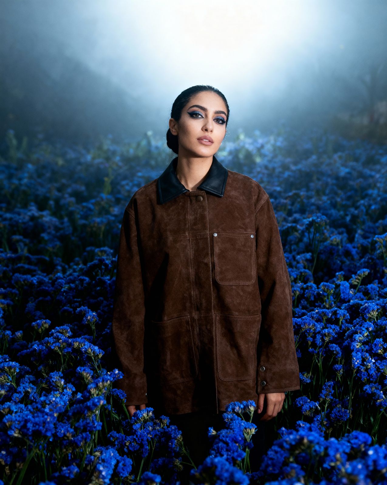 a woman standing in a field of blue flowers