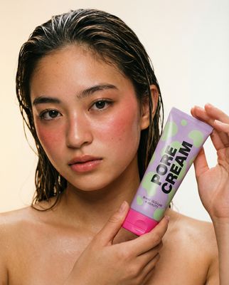 a woman is holding a tube of cream