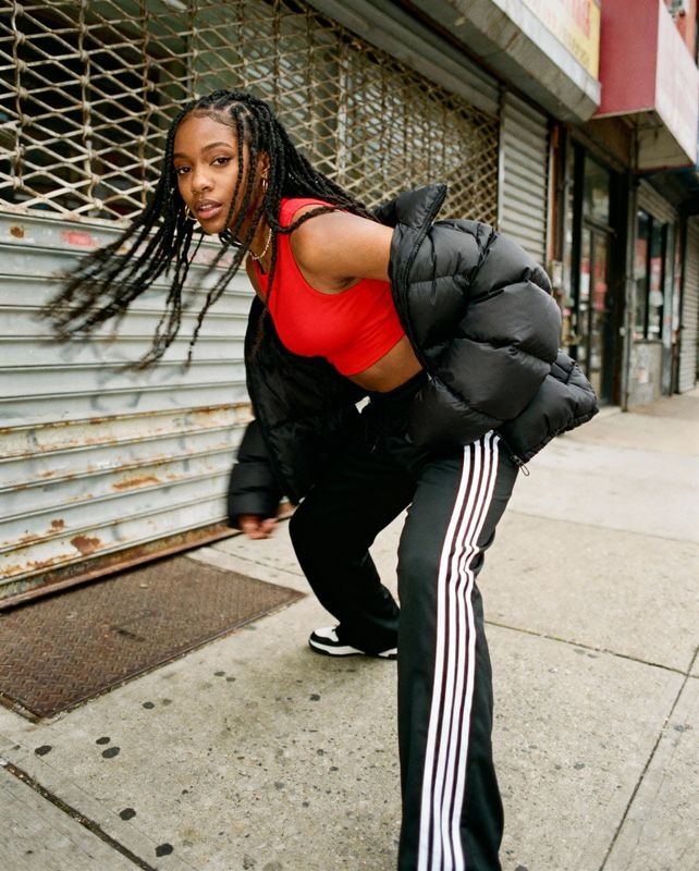 a woman with dreadlocks is leaning against a wall
