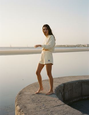 a woman standing on a ledge near the water