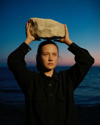 a woman holding a rock over her head