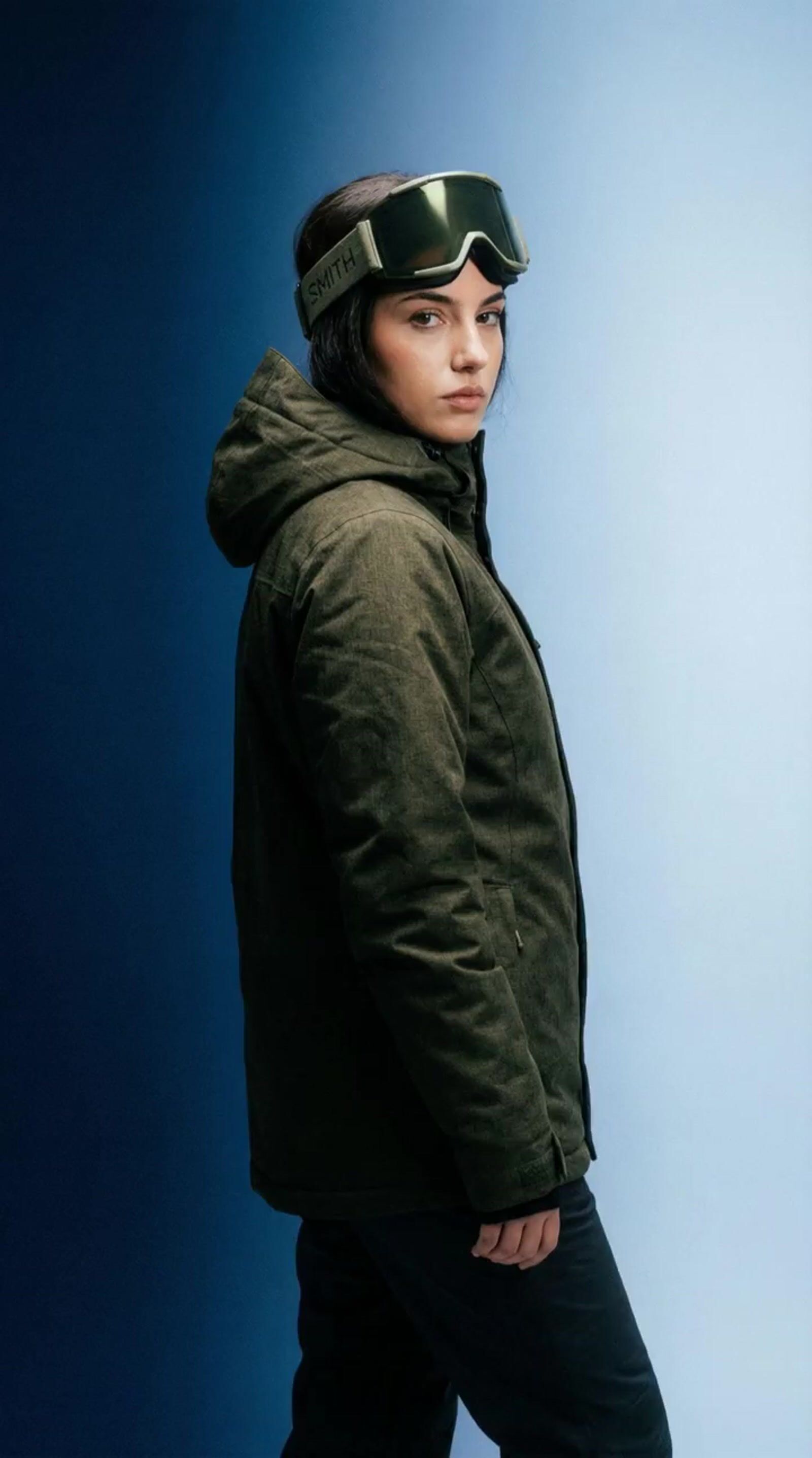 a woman in a green jacket and goggles