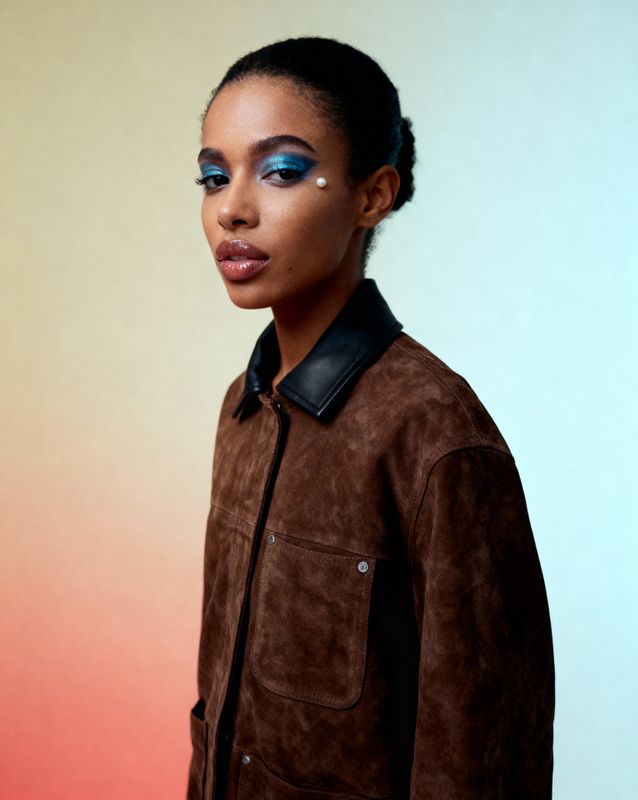 a woman with blue makeup and a brown jacket